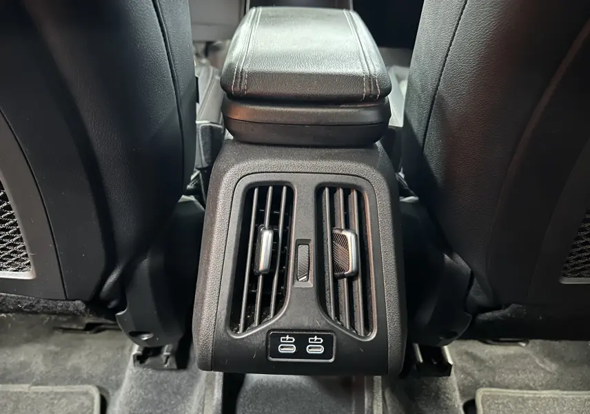 Vue rapprochée des aérateurs arrière et ports USB entre les sièges noirs d’une BMW Série 2 Active Tourer blanche.