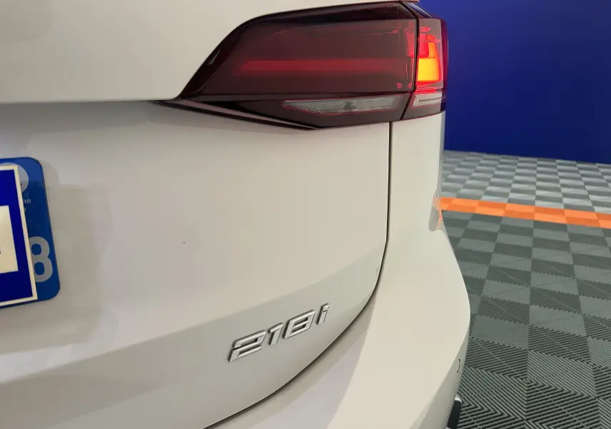 Gros plan sur le feu arrière droit et le badge 216i d’une BMW Série 2 Active Tourer blanche, arrière du véhicule.