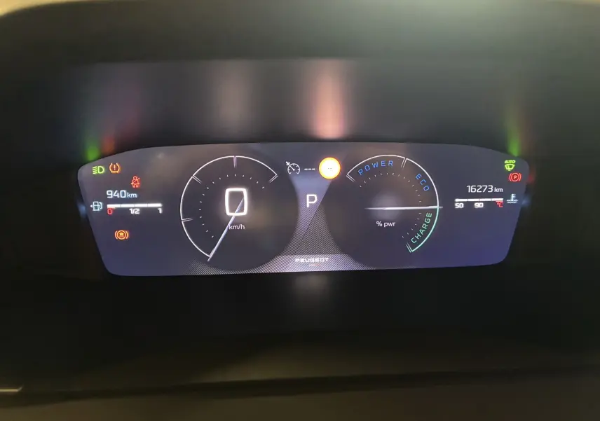 Tableau de bord numérique de la Peugeot 2008 hybride 2025, affichant vitesse, autonomie et indicateurs d'alerte.