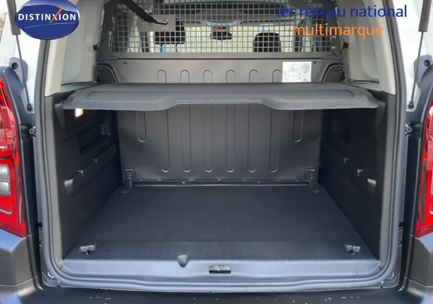 Vue arrière du coffre ouvert d'un Citroën Berlingo Multispace blanc glacier, montrant la séparation intérieure et la tablette de rangement.