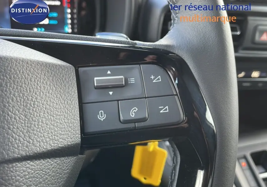 Gros plan sur les commandes au volant du Citroën Berlingo blanc glacier, avec boutons de volume et téléphone visibles.