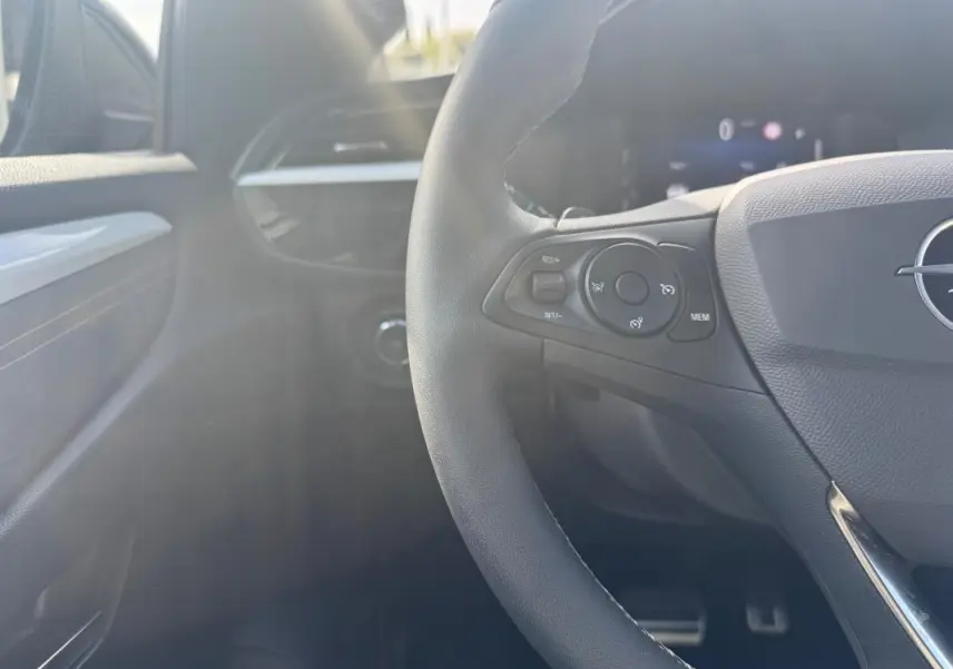 Gros plan sur le volant côté gauche de l’Opel Corsa noir 2025, avec commandes intégrées et tableau de bord en arrière-plan flou.
