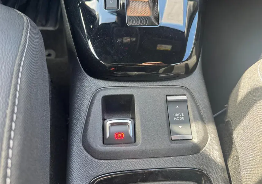 Vue rapprochée de la console centrale de l’Opel Corsa noire 2025, avec frein à main électronique et bouton Drive Mode.