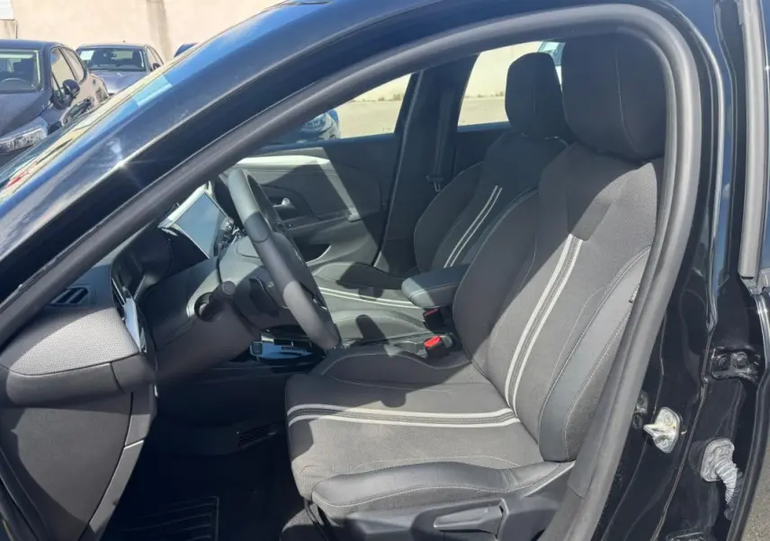 Vue intérieure côté conducteur de l’Opel Corsa 2025 noire, montrant les sièges tissu avec bandes claires et le tableau de bord moderne.