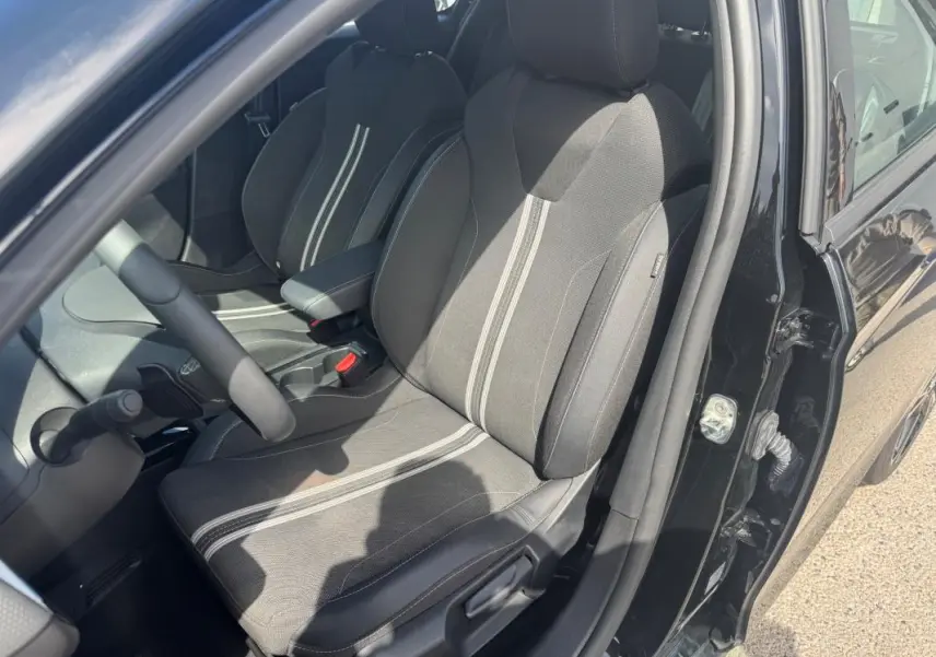Vue intérieure côté conducteur de l’Opel Corsa 2025 noire, mettant en valeur les sièges tissu avec bandes centrales claires.