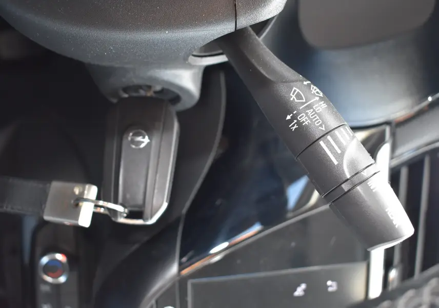 Gros plan sur la manette d'essuie-glace et la clé de contact avec logo Opel dans l'habitacle d'une Opel Corsa gris 2021.