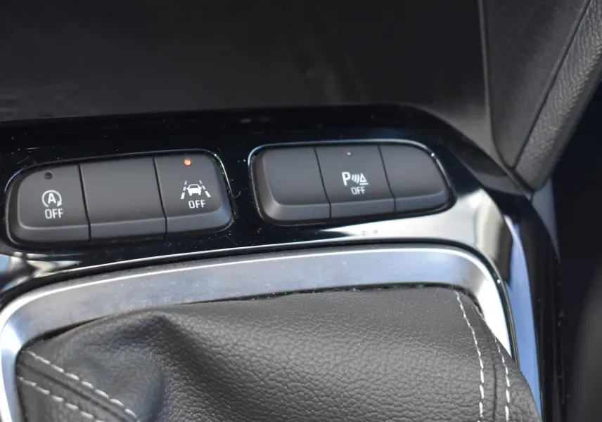 Gros plan sur les boutons de contrôle et soufflet de levier de vitesse en cuir noir de l'Opel Corsa 1.2 Turbo essence.