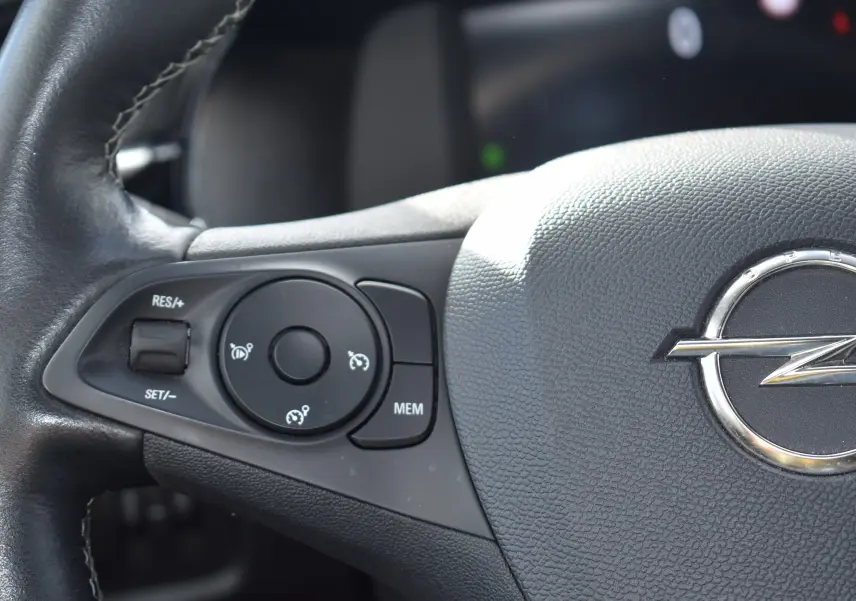 Gros plan sur le volant en cuir noir d'une Opel Corsa 2021 avec commandes de régulateur de vitesse intégrées.