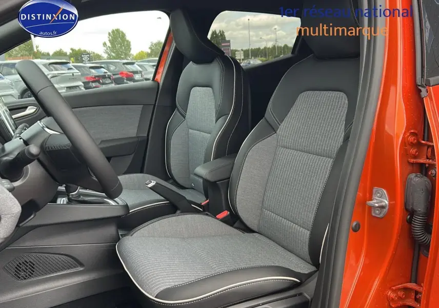 Intérieur de la Renault Clio V orange Valencia, vue côté droit sur les sièges avant sport gris avec surpiqûres blanches.