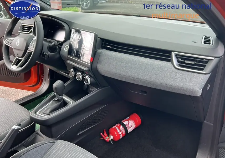 Intérieur avant droit de la Renault Clio V orange Valencia, tableau de bord moderne avec écran tactile et extincteur au sol.