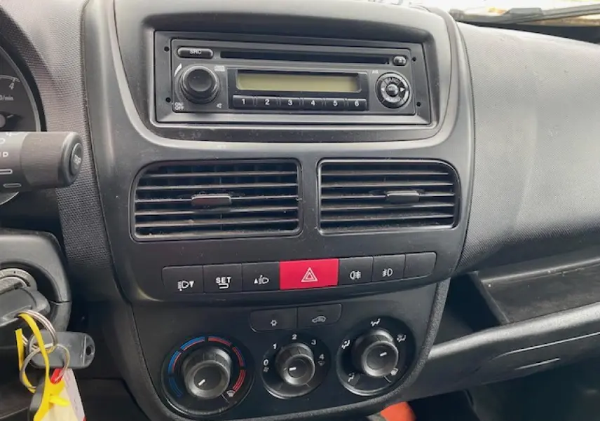 Tableau de bord intérieur de l'Opel Combo blanc 2016, vue frontale centrée sur la console avec autoradio et commandes climatiques.