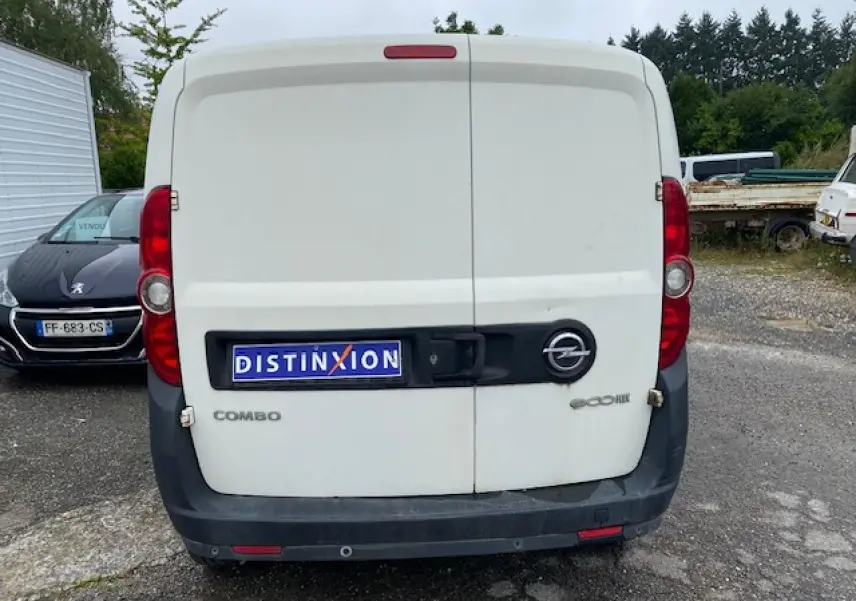 Vue arrière d'un utilitaire Opel Combo blanc avec portes arrière tôlées et logo distinctif sur parking.