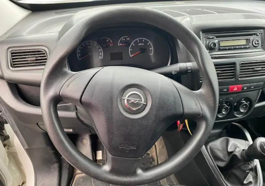 Vue rapprochée du volant Opel Combo L2H1 2016, tableau de bord noir avec autoradio et commandes manuelles visibles.