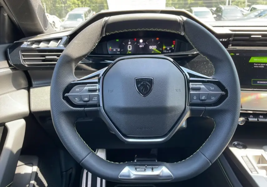 Vue rapprochée du volant cuir perforé de la Peugeot 308 GT 2025 avec logo lion et badge GT visible.