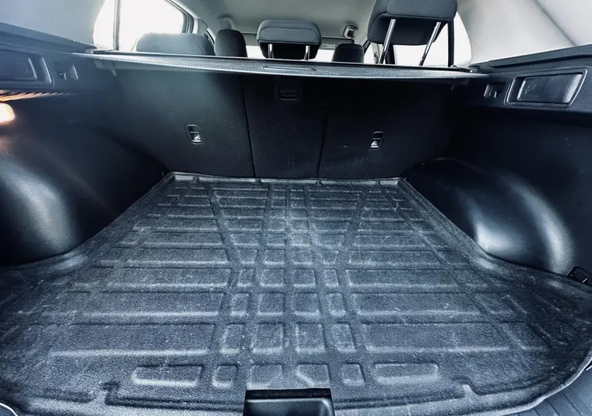 Vue intérieure du coffre noir du Kia Sportage 2023 avec banquette arrière et cache-bagages visibles.