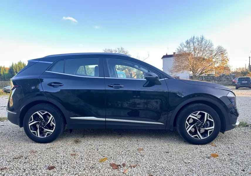 Profil côté gauche du Kia Sportage noir 2023 avec jantes alliage et détails chromés sur les bas de caisse.