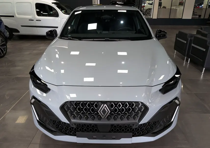 Vue avant rapprochée d’une Renault Clio VI TCe 115 CH TECHNO gris Rafale avec calandre hexagonale et phares LED noirs.