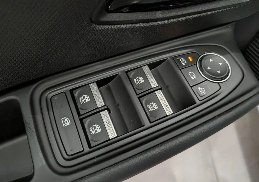 Gros plan sur les commandes de lève-vitres et réglage des rétroviseurs côté conducteur d'une Renault Clio VI TCe 115 Gris Rafale.