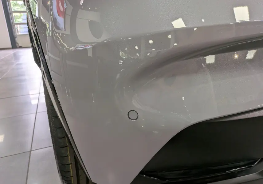 Gros plan sur l'aile avant gauche gris Rafale de la Renault Clio VI TCe 115 CH TECHNO avec capteur de stationnement visible.
