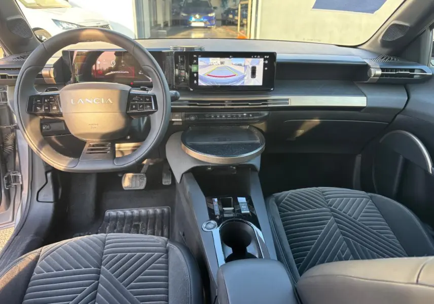 Vue intérieure avant de la Lancia Ypsilon gris, avec tableau de bord moderne et écran tactile affichant la caméra de recul.