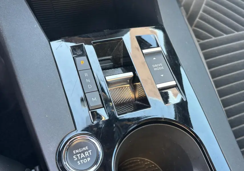 Gros plan sur la console centrale noire brillante de la Lancia Ypsilon hybride avec boutons de boîte auto et démarrage start/stop.