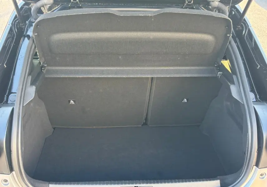Vue plongeante sur le coffre ouvert d'une Lancia Ypsilon gris 2025, montrant un espace de rangement propre et vide.