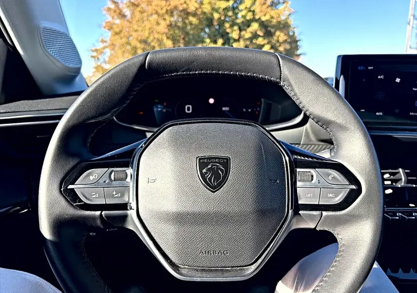Vue rapprochée du volant cuir noir de la Peugeot 208 1.2 100 allure avec commandes intégrées et tableau de bord digital.