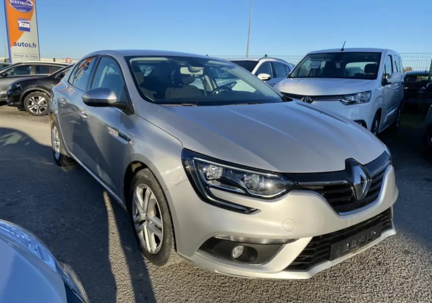 Renault Mégane Sedan gris platine vue 3/4 avant avec projecteurs antibrouillard et calandre noire brillante.