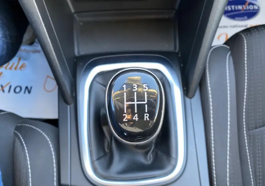 Le levier de vitesses manuel noir de la Renault Mégane gris platine, vu de dessus, avec coutures blanches sur les sièges.