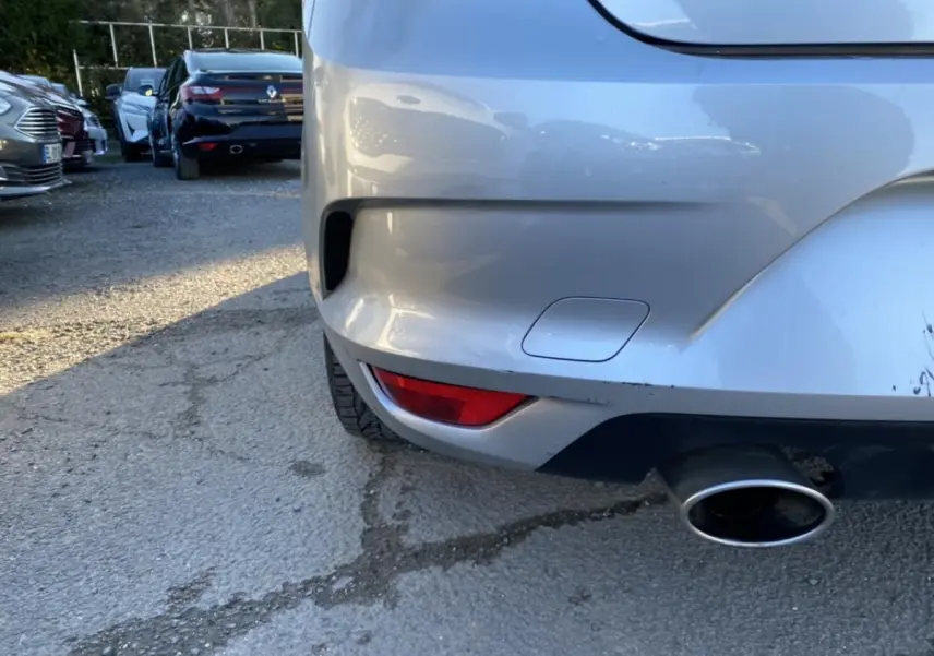 Gros plan sur le coin arrière droit gris platine d'une Renault Mégane avec sortie d'échappement visible.