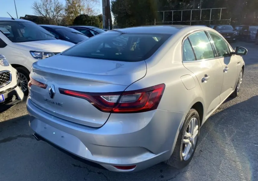 Vue 3/4 arrière droite d'une Renault Mégane Sedan gris platine, avec feux arrière LED et jantes alliage visibles.
