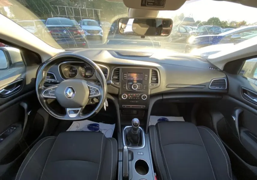 Vue intérieure avant de la Renault Mégane gris platine 2017, avec volant multifonctions et boîte manuelle.