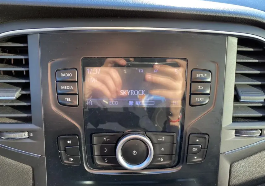 Détail de la console centrale de la Renault Mégane gris platine, avec écran radio affichant la station Skyrock.