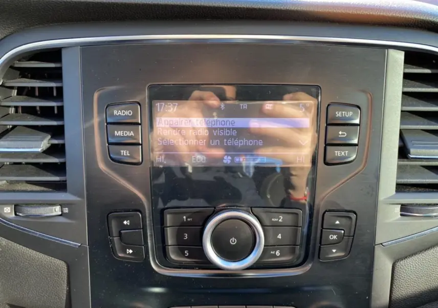 Gros plan sur la console centrale de la Renault Mégane gris platine, affichant l'écran multimédia et les commandes audio.