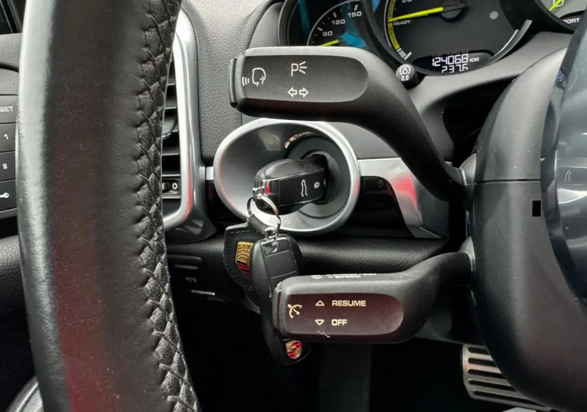 Gros plan sur le volant cuir et le contacteur avec clé Porsche dans le tableau de bord du Cayenne noir 2017.