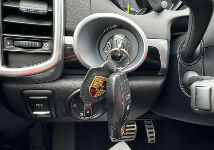 Gros plan sur le contacteur avec clé Porsche suspendue dans l'habitacle noir du Cayenne 2017.