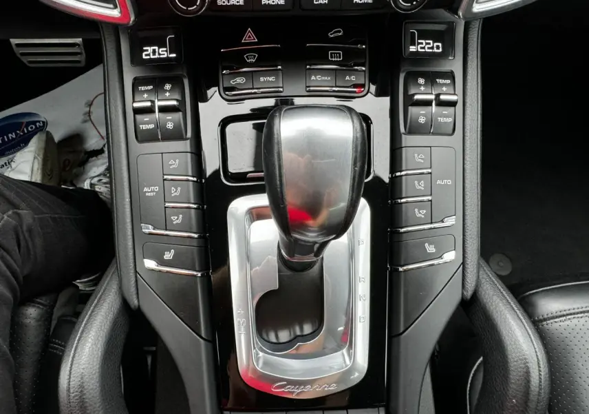 Vue rapprochée de la console centrale noire du Porsche Cayenne 2017 avec levier de vitesses automatique et commandes climatisation.