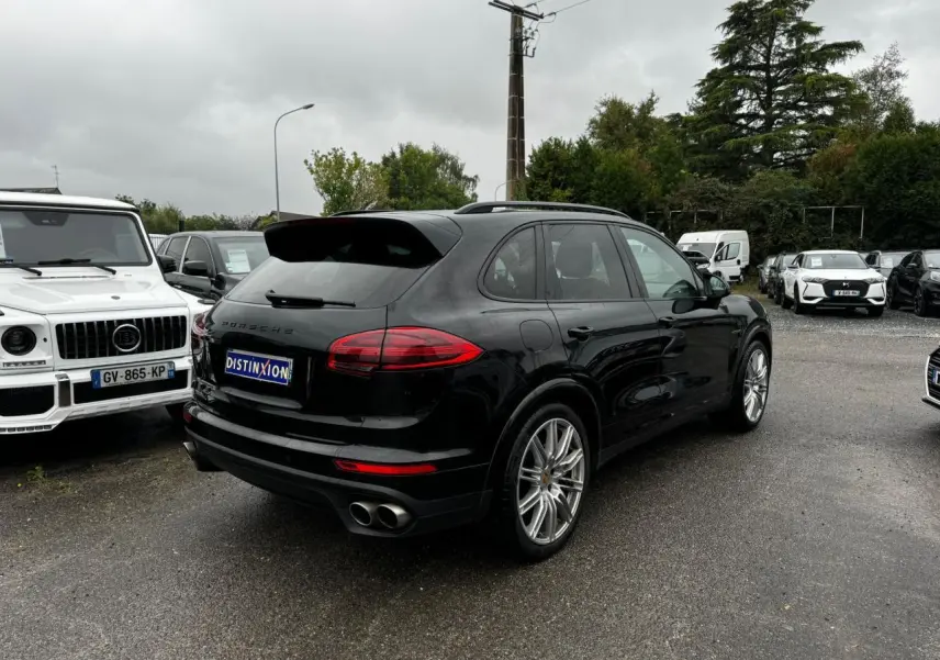 Vue 3/4 arrière droite d'un Porsche Cayenne noir avec jantes 21 pouces et double sortie d'échappement chromée sportive.