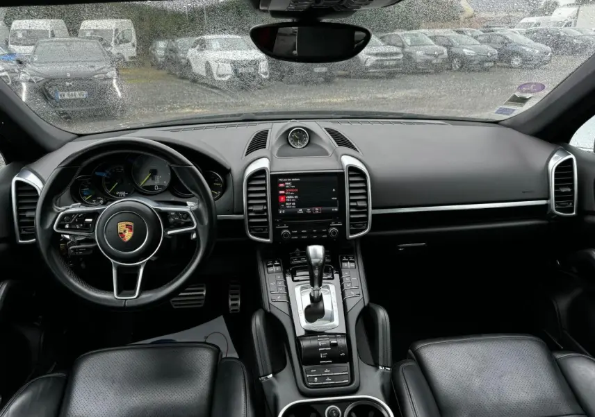 Intérieur noir du Porsche Cayenne 2017 vu de face, avec volant cuir, console centrale et écran tactile visible.