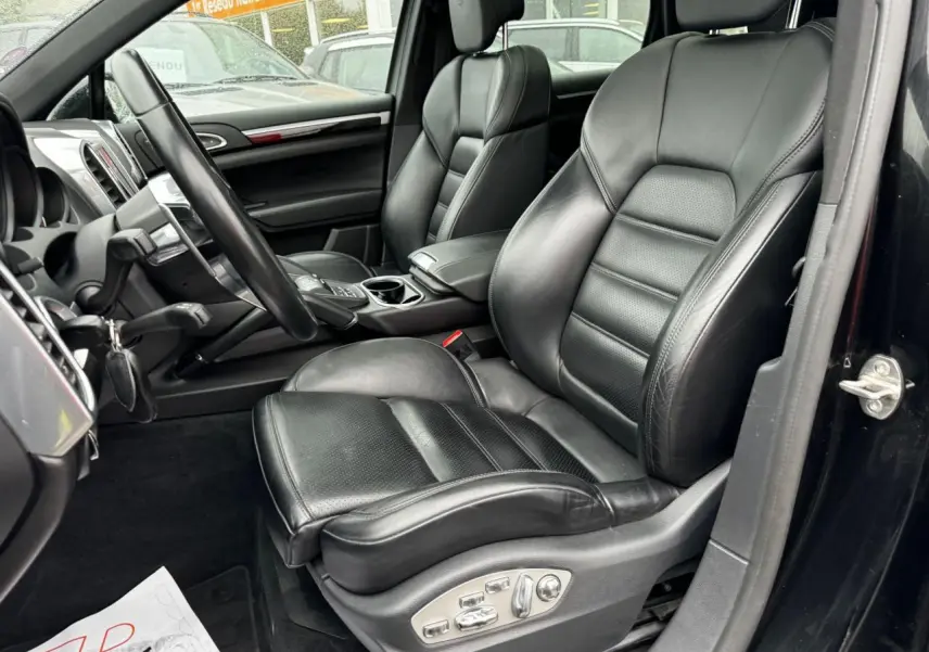 Intérieur noir du Porsche Cayenne 2017 vu côté conducteur, mettant en valeur les sièges sport en cuir et le volant multifonctions.