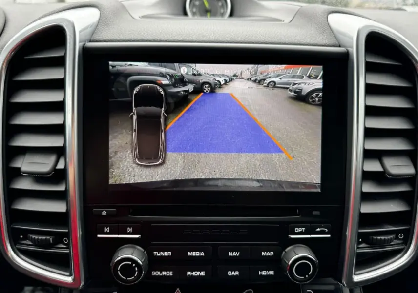 Affichage caméra de recul sur écran central du tableau de bord d'un Porsche Cayenne noir, vue intérieure frontale.