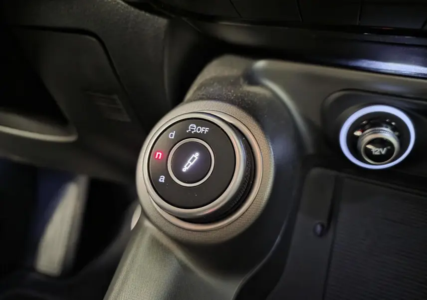 Gros plan sur le sélecteur de modes de conduite Alfa DNA et prise 12V dans l'habitacle noir de l'Alfa Romeo Tonale Vert.