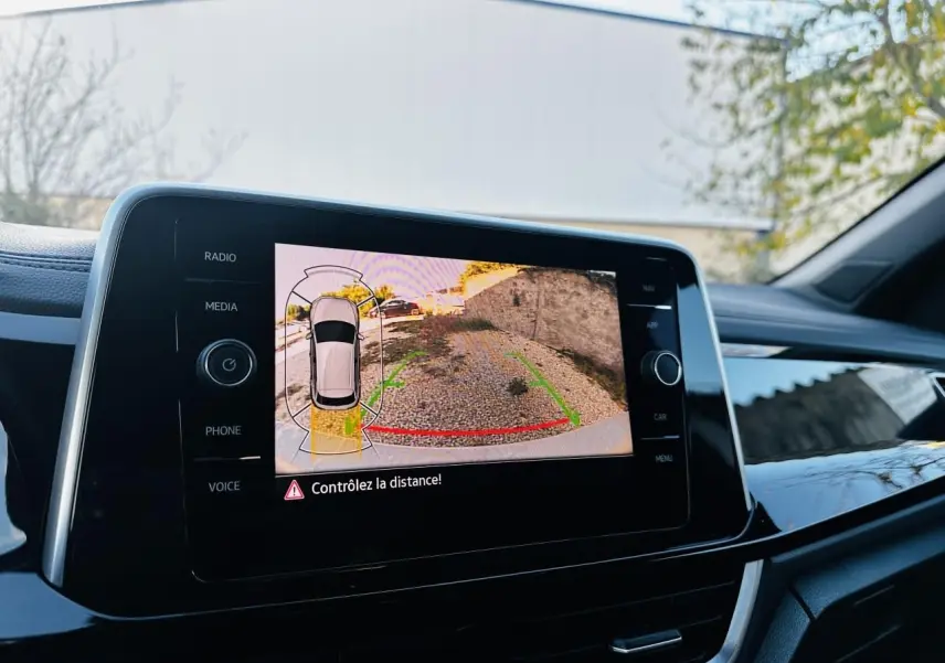 Écran tactile intérieur du Volkswagen T-Roc 2024 affichant la caméra de recul avec alertes de distance.
