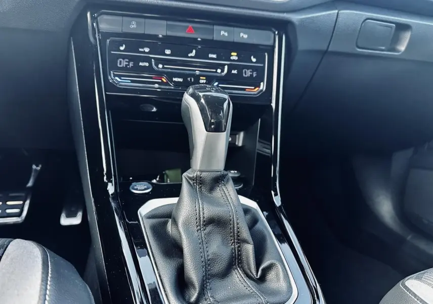 Gros plan sur la console centrale du Volkswagen T-Roc 2024 avec levier de boîte auto DSG et commandes climatisation tactile.