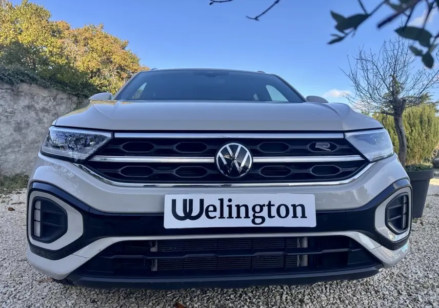 Vue frontale d'un Volkswagen T-Roc gris avec calandre R-Line et logo VW bien visible.