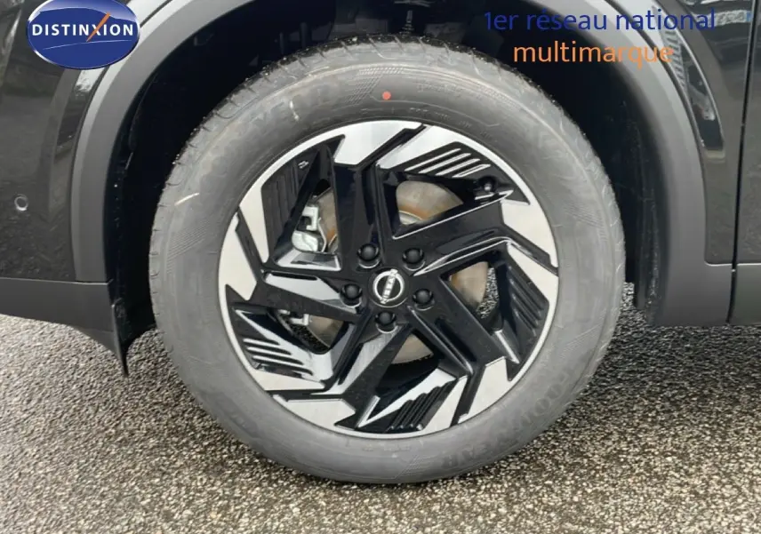 Gros plan sur la roue avant droite du Nissan Qashqai noir perle métal avec jante alliage au design moderne.