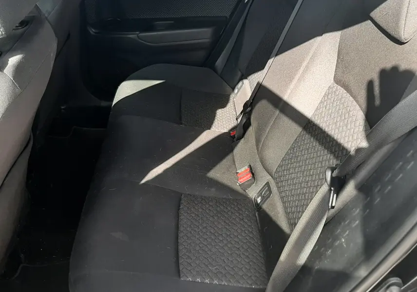 Vue intérieure côté conducteur du Toyota C-HR 1.8 Hybrid 122 Design 2023 avec sièges tissu noir et console centrale.