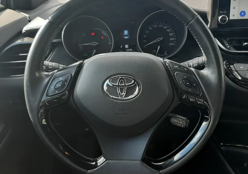Vue intérieure avant du Toyota C-HR 1.8 Hybrid 122 Design 2023 noir, tableau de bord et volant multifonctions visibles.
