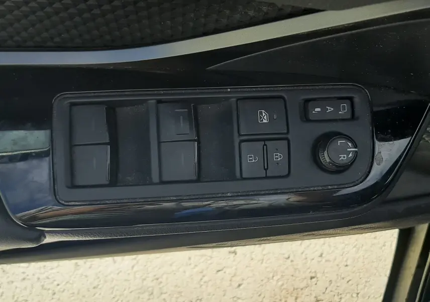 Vue intérieure centrée sur l'accoudoir et la console centrale noire du Toyota C-HR 1.8 Hybrid 2023 avec sièges tissu noirs.