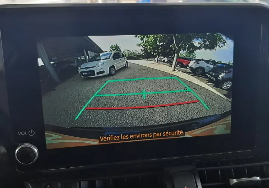 Vue rapprochée de la console centrale noire du Toyota C-HR 1.8 Hybrid 2023 avec écran tactile et commandes climatisation digitales.